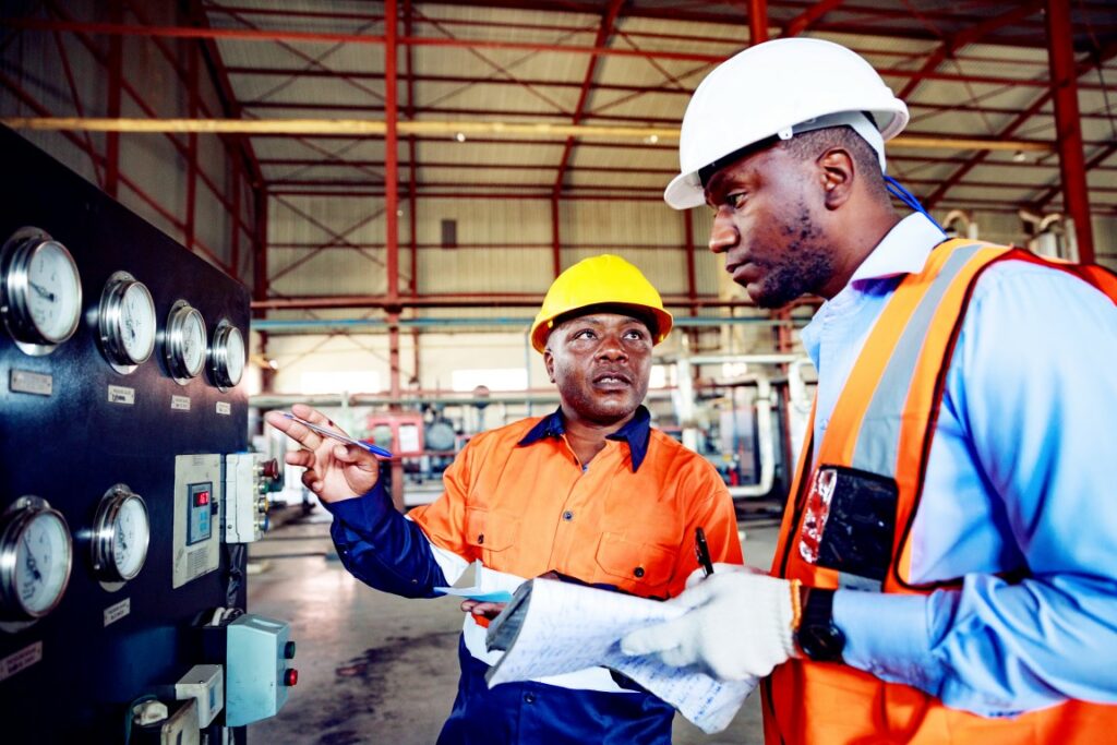 Safety Inspector Checks the Series of Pressure Gauges with a Factory Worker